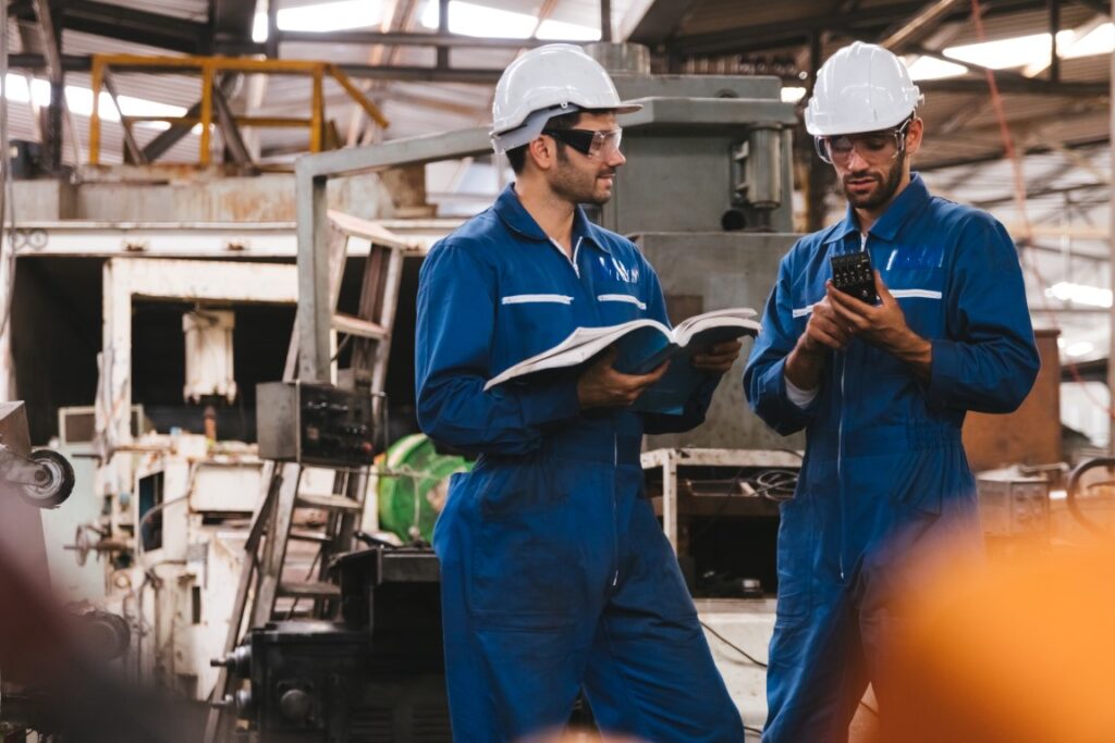 Employés d’usine consultant un manuel de maintenance et lubrification.