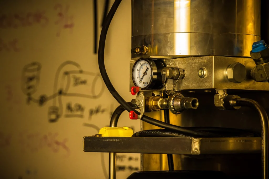 Pressure gauge and valves of an industrial lubrication system in a laboratory.